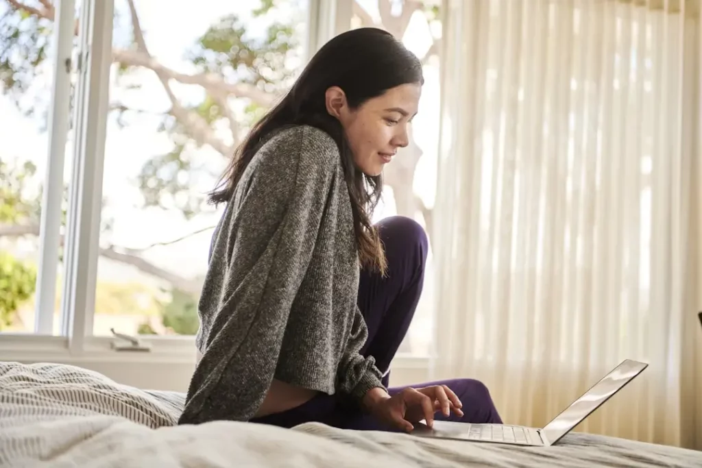 woman-with-laptop A woman utilizing a customer self-service knowledge base at home exemplifies how can a self-service knowledge base help enhance customer satisfaction